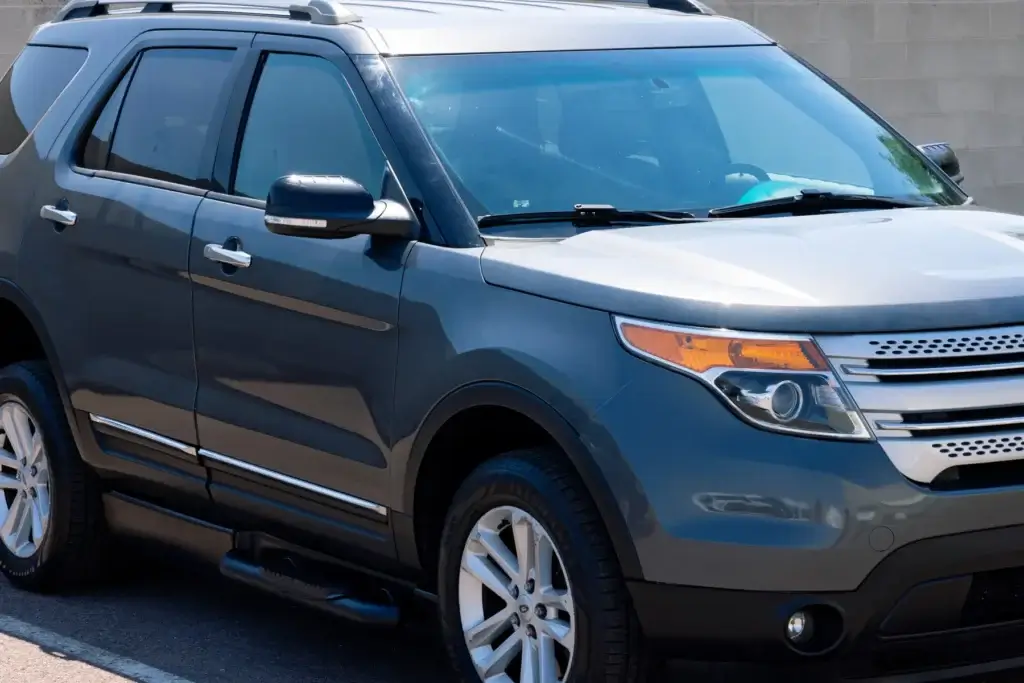 A gray SUV parked on the street next to a concrete wall, with visible front and side details.