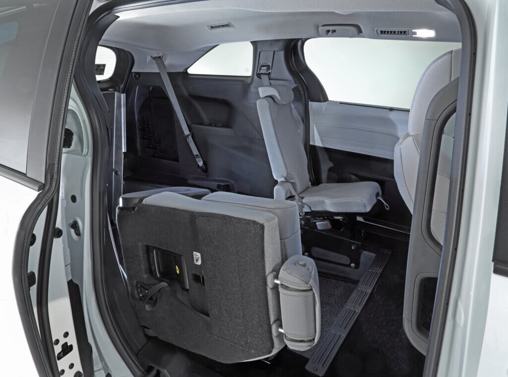 Interior view of a vehicle showing a folded second-row seat, revealing access to the third-row seating area.