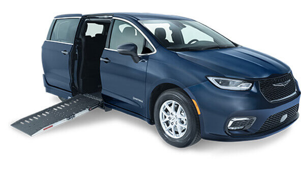 Blue minivan with a side door open, featuring an extended wheelchair ramp for accessible entry.